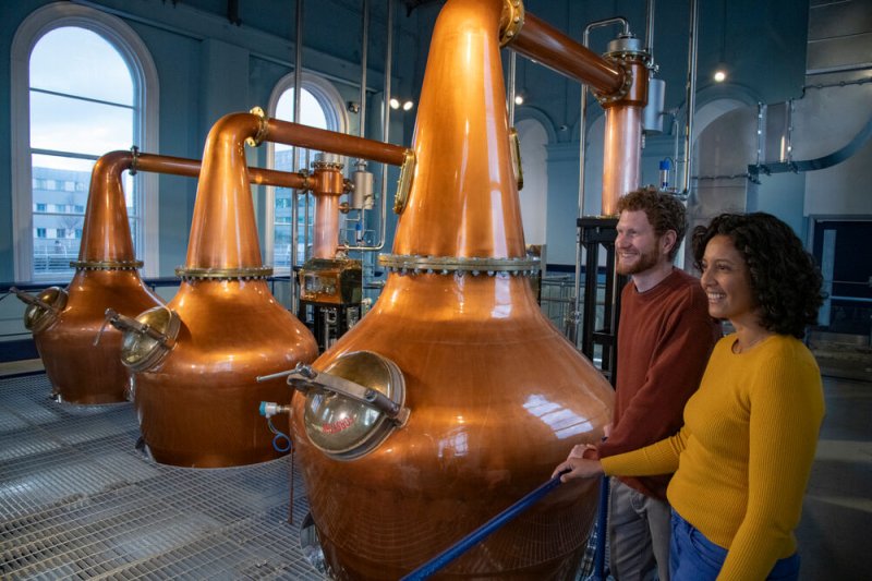 Titanic Distillers credit to chrishillphotographer two people looking at whiskey distilling equipment