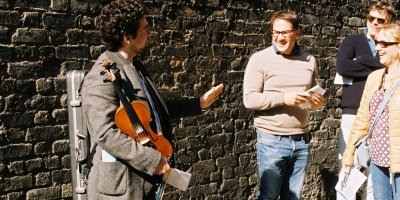 Original Dublin Music tour Man wearing grey suit holding violin standing outside at brick wall giving a music tour