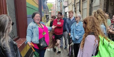 Original Dublin Queer tour 2 Tour guide speaking to group. Tour guide wearing bright pink top